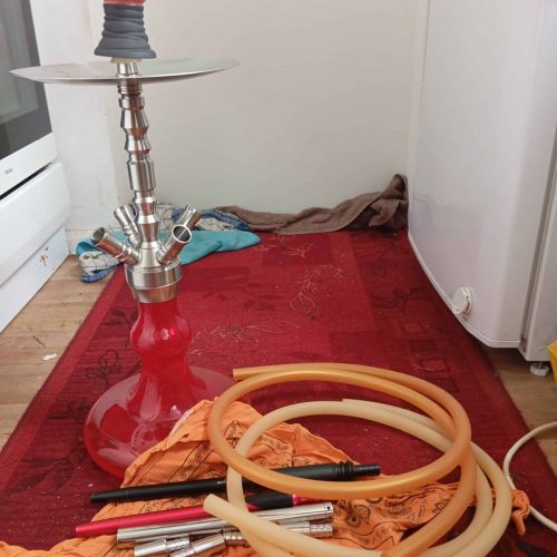 Shisha mit Zubehör auf Teppich, Rauchsäule, Schläuche und Kohle.