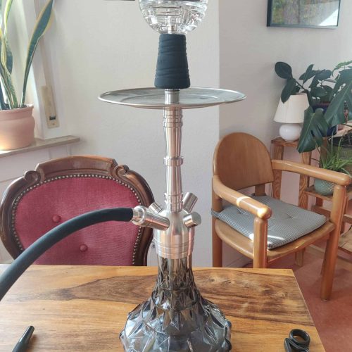 Shisha-Rauchsäule mit Kopf und Schlauch in einem Wohnzimmer.