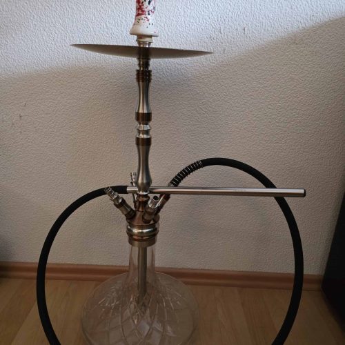 Hookah mit Glasbasis, Metallaufsatz und Schlauch, auf Holzboden.