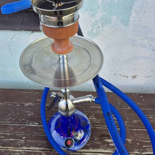 Shisha mit Wasserpfeife, inklusive Tabak und Schlauch, auf Holztisch.