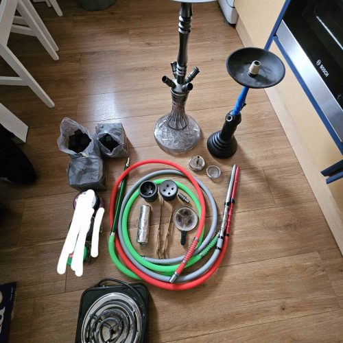 Shisha mit Zubehör, Kohle, Schlauch und Ersatzteile auf Holzboden.