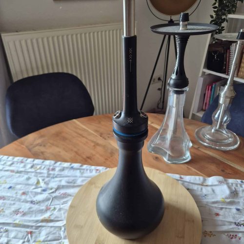 Stilvolle Wasserpfeife mit Glas- und Metallteilen auf Holztisch.
