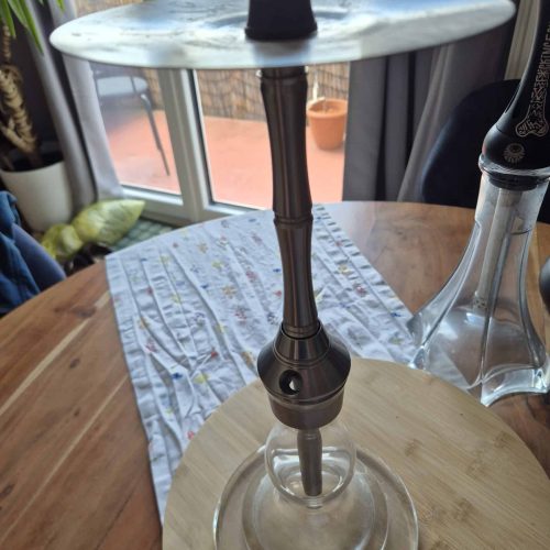 Shisha mit schwarzem Kopf auf Glas- und Holzständer, Innenaufnahme.