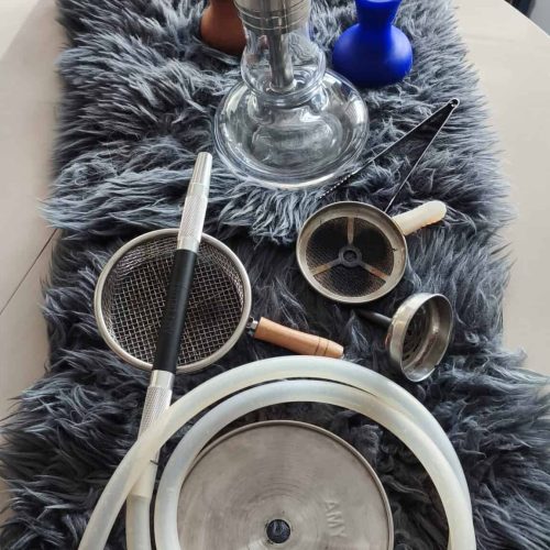 Verschiedene Shisha-Accessoires auf einer Tischdecke.
