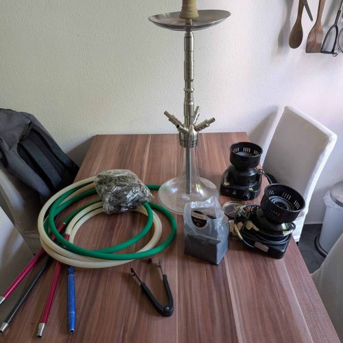 Rauchsäule mit Schlauch, Kohlezange und Zubehör auf Tisch.