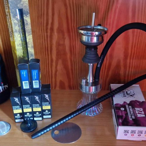 Shisha mit Glasbowl, Kohle, Zange und Zubehör auf Holz.