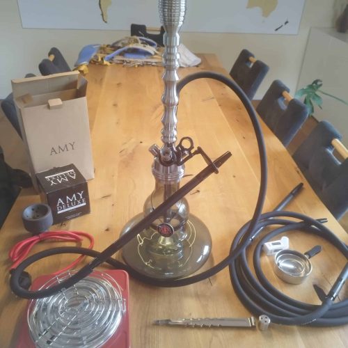 Shisha-Kohleanzünder mit Glasbowl, Schlauch und Zange auf Tisch.