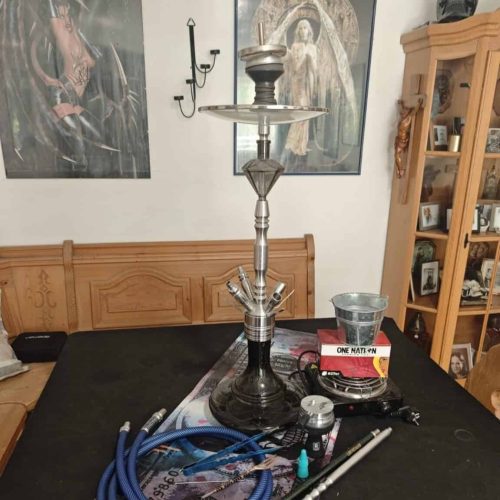 Shisha mit Glasbowl, Schlauch und Kohle auf Tisch.