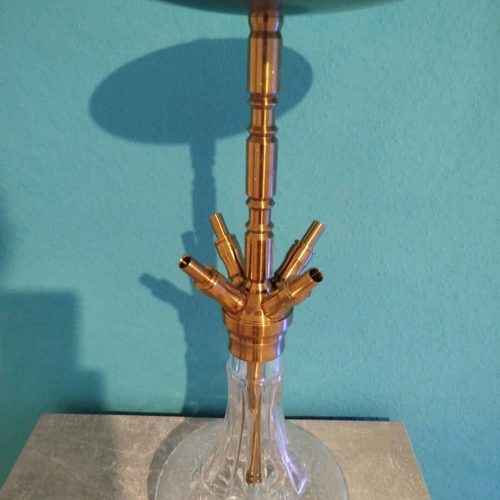 Shisha-Hookah mit goldener Metallstange und Glasbowl auf grauem Tisch.