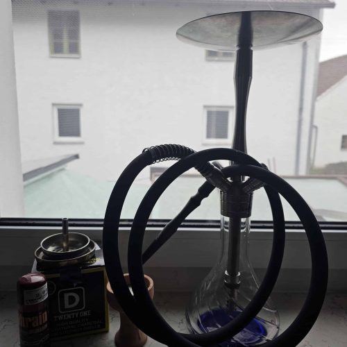 Wasserpfeife mit Wasser und Zubehör auf Fensterbank.