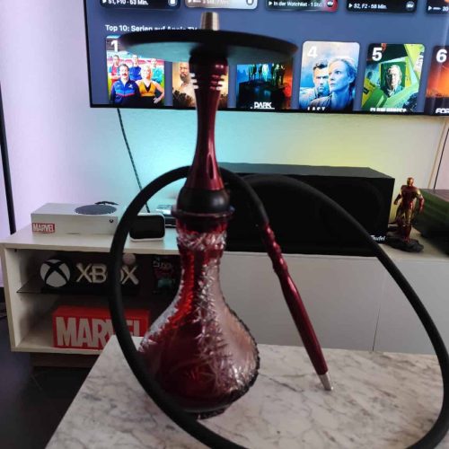 Shisha mit roter Glasbowl auf Tisch vor Fernseher im Wohnzimmer.
