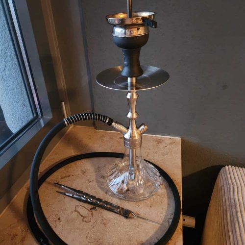 Schwarze Shisha mit Glasbowl und Metallaufsatz auf Tisch.