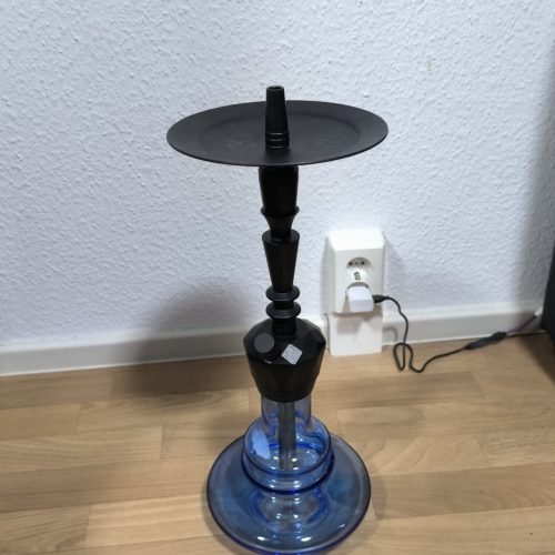 Wasserpfeife mit Rauchfackel und Zubehör auf Holzboden.