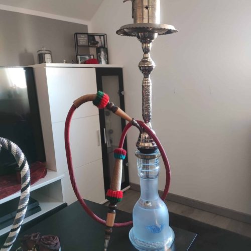 Shisha mit Metall- und Glas-Elementen, auf einem Tisch in einem modernen Wohnzimmer.