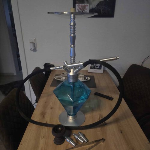 Shisha mit blauer Glasbasis und Metallrohr, auf einem Holztisch.