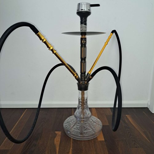 Shisha mit Glasbasis und Metallaufsatz, zwei Schläuche, auf Holzboden stehend.