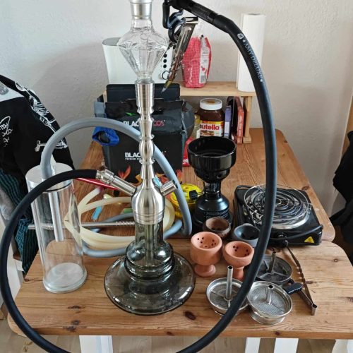 Shisha mit Glasbowl, Schlauch und Tabakzubehör.