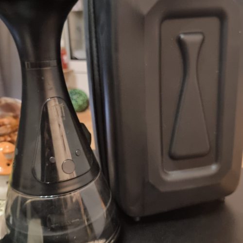 Kaffeebereiter mit Glasbehälter neben einem schwarzen Koffer.
