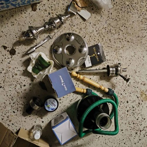 Verschiedene Shisha-Teile, Zubehör und Ersatzteile auf einem Tisch verteilt.
