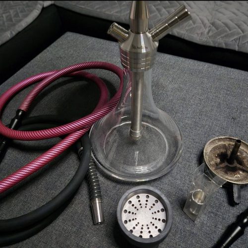 Rauchsäule mit Schlauch und Zubehör für Shisha, auf einer Tischplatte.