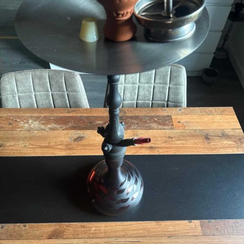 Wasserpfeife mit Tabak und Zubehör auf einem Tisch, ideal für Shisha-Liebhaber.