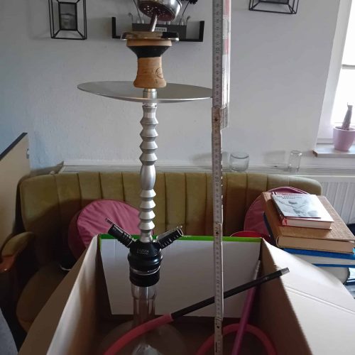 Shisha mit Wasserpfeife und Schlauch, auf einem Tisch in einem Wohnzimmer.