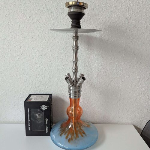 Moderne Shisha mit Glasbasis und Metallteilen auf weißem Tisch.