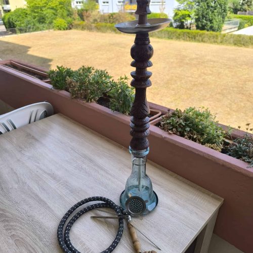 Schwarzer Shisha-Kamin mit Glasbowl auf Balkon im Freien.