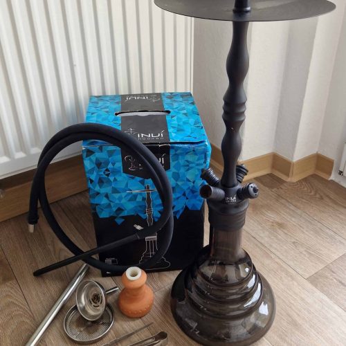 Shisha mit Zubehör, Ersatzteile und Tabak, auf Holzboden in Raum.