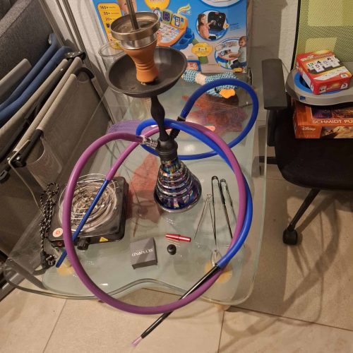 Rauchsäule mit Shisha, Schlauch und Zubehör auf einem Tisch, ideal für Raucher und Shisha-Liebhaber.