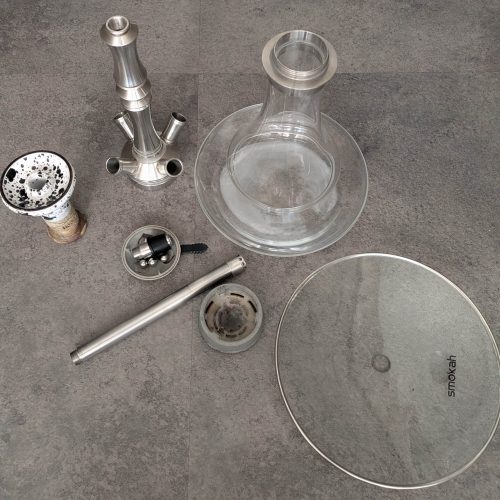 Verschiedene Shisha-Teile, inklusive Glasbowl und Metallkomponenten.