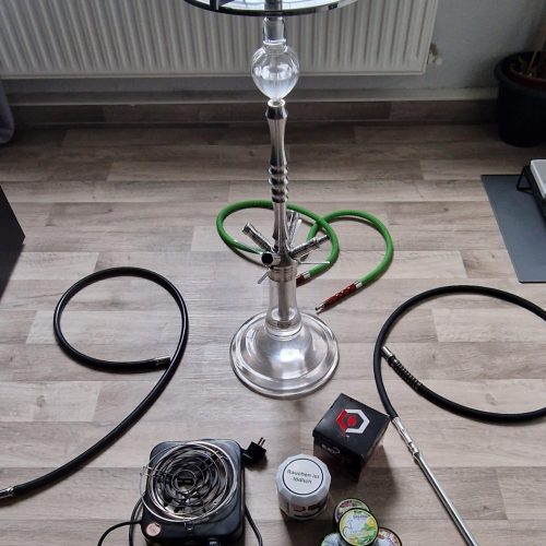 Rauchsäule mit Shisha, Schlauch, Tabak und Zubehör auf Holzboden.