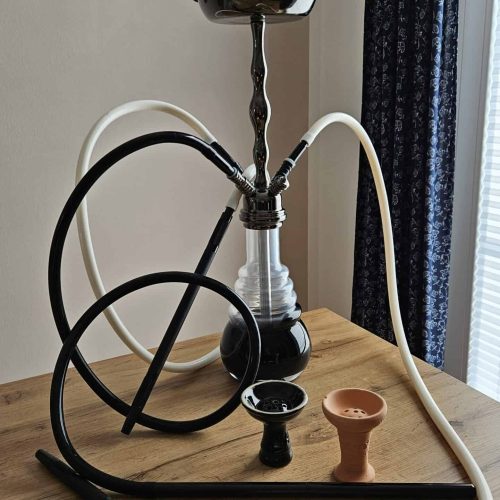 Shisha mit Glasbowl, Schlauch und Tabakkopf auf Holz.