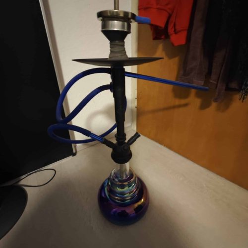 Hookah mit Glasbasis und Schlauch, auf Boden stehend.