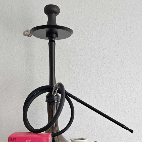 Moderne schwarze Shisha mit Glasaufsatz und Zubehör, auf weißem Hintergrund.