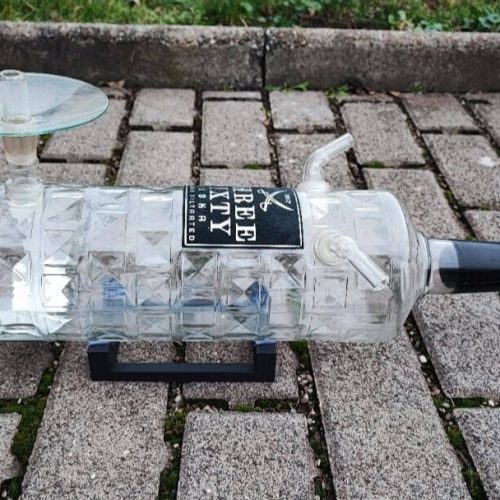 Alkoholflasche umfunktioniert als Shisha-Adapter, auf Pflastersteinen liegend.