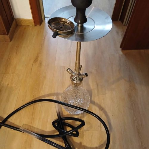 Shisha mit Glasbase, Schlauch und Zubehör im Raum.