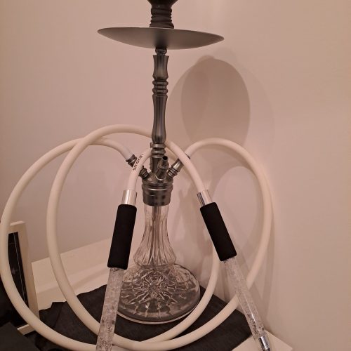 Rauch-Hookah mit Glasbasis, zwei Schläuchen und Metallaufsatz, auf schwarzem Untergrund.