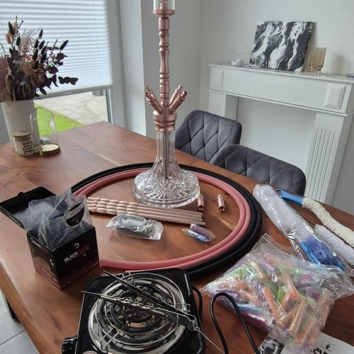 Shisha-Kopf mit Glasbowl auf einem Tisch, Zubehör und Verpackung.