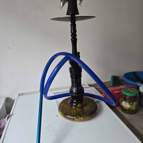 Rauchende Wasserpfeife auf einem Tisch, Shisha mit blauer Schlauch und Wasserbehälter.