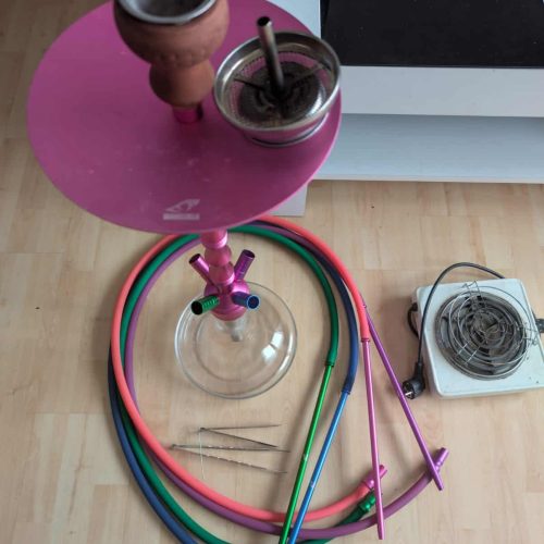 Shisha mit bunten Schläuchen und Zubehör, auf Holztisch, für Raucher und Shisha-Liebhaber.