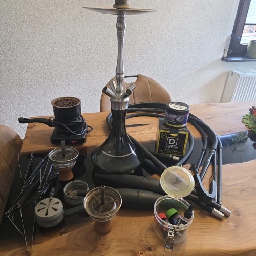 Shisha mit Zubehör auf Tisch, Rauchsäule, Tabak, Kohle, Zange.