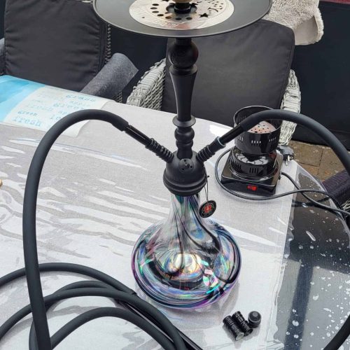 Shisha mit Glasbowl, Schlauch und Tabakkopf auf Tisch.