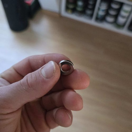 Ring als Schmuckstück, gehalten in der Hand vor einem Regal mit Flaschen.
