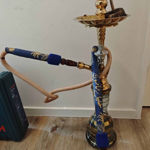 Shisha mit goldener Bowl, blauer Dekoration und Schlauch, auf Holzboden stehend.