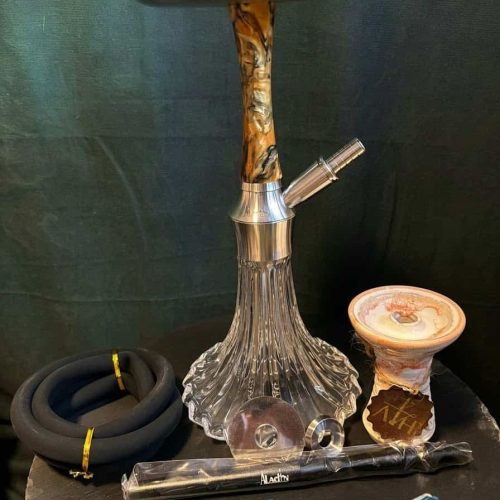 Shisha-Kopf mit Glasbowl, Schlauch und Zubehör auf schwarzem Tisch.