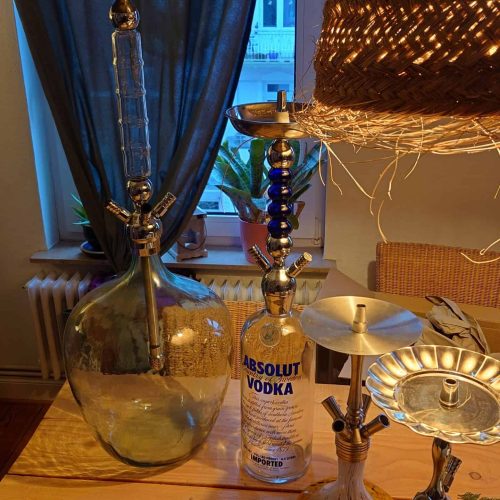 Shisha mit Wasserpfeife und Spirituosenflasche auf Tisch.