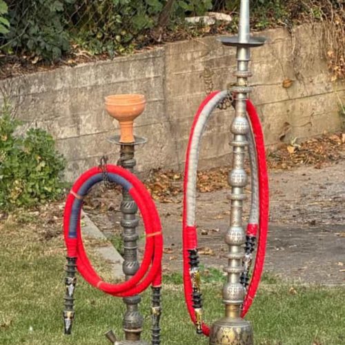 Zwei antike Shishas mit Schläuchen im Garten, bereit zum Rauchen.