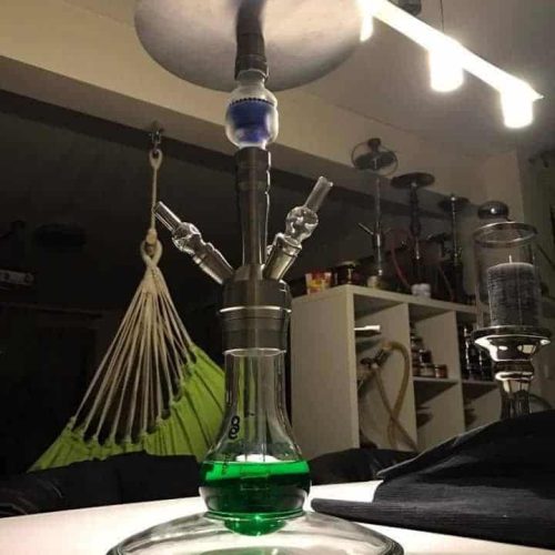 Shisha mit grünem Wasser und Metallaufsatz im Wohnzimmer.