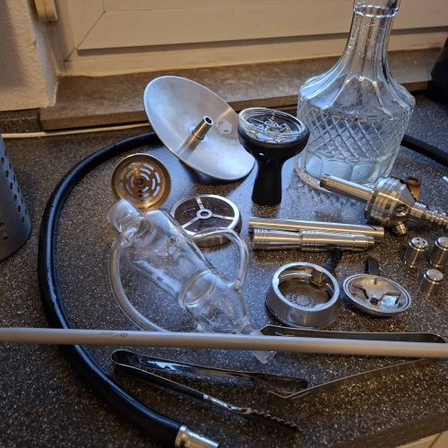 Verschiedene Glas-Shisha-Teile und Zubehör auf der Fensterbank.